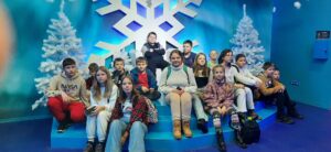 Grupa uczniów siedzi na podeście w niebieskim pomieszczeniu w stylistyce zimowej