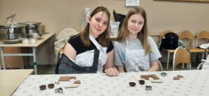 Dwie uczennice pozują do zdjęcia na warsztatach czekoladowych.