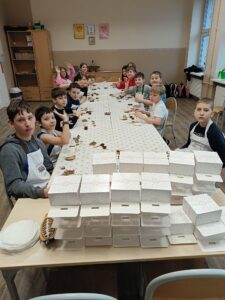 Grupa uczniów bierze udział w warsztatach czekoladowych.