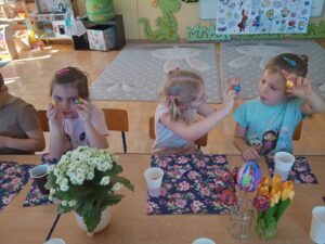 Trzy dziewczynki z przedszkola prezentują swoje wielkanocne prace plastyczne
