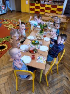 Grupa dzieci przy posiłku wielkanocnym.