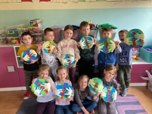 Grupa dzieci prezentuje prace plastyczne na obchodach Światowego Dnia Ziemi
