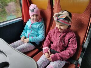 Dwie uśmiechnięte dziewczynki pozują do zdjęcia w autobusie