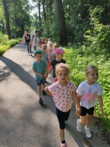 Grupa dzieci przedszkolnych idzie leśną drogą