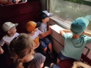 Grupa dzieci w pociągu patrzy przez okno
