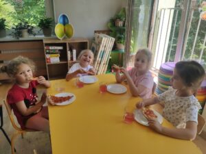 Przedszkolaki jedzą posiłek przy żółtym stole