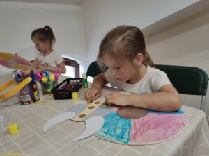 Dwie dziewczynki w wieku przedszkolnym wykonują prace plastyczną o tematyce wikingów