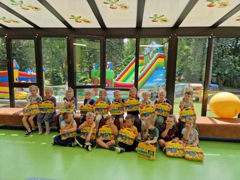 Przedszkolaki pozują do zdjęcia z pudełkami klocków lego